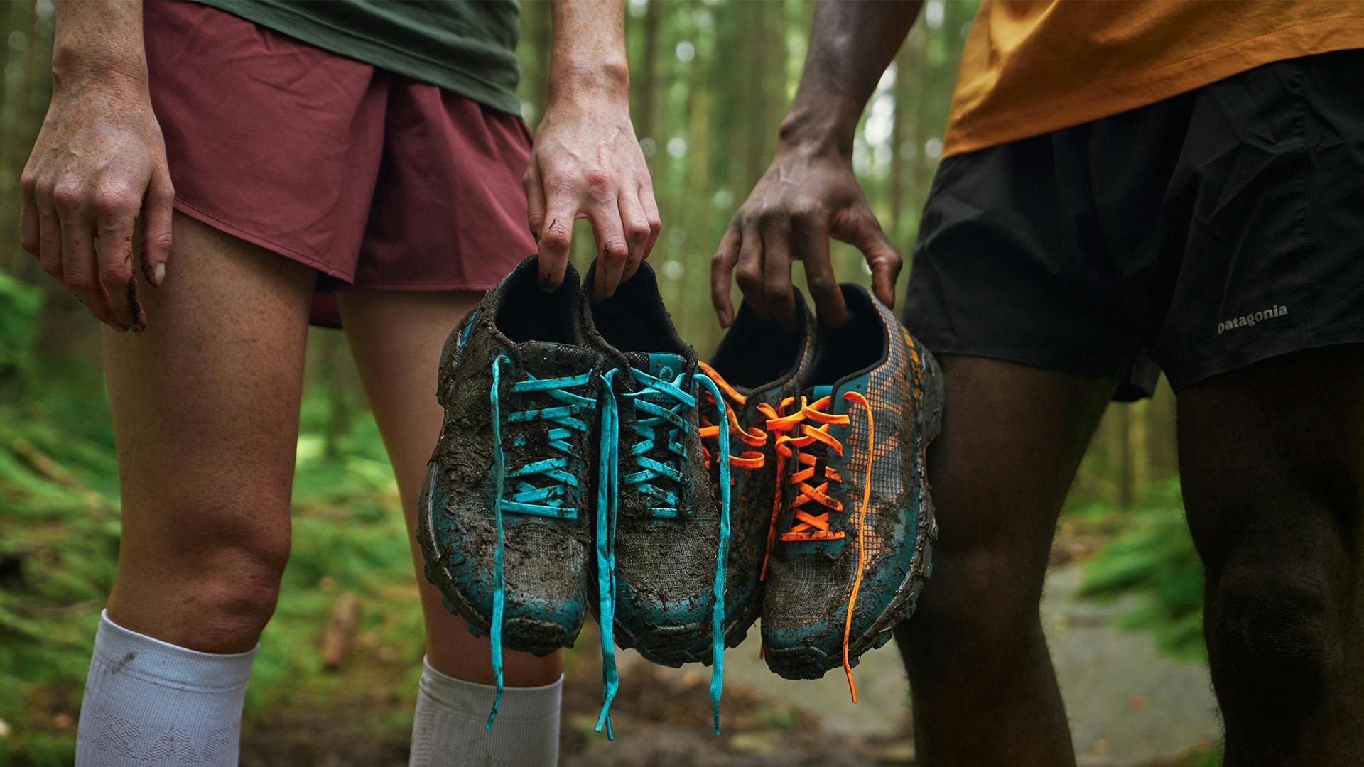 Two people holding up two pairs of Icebug trail running shoes